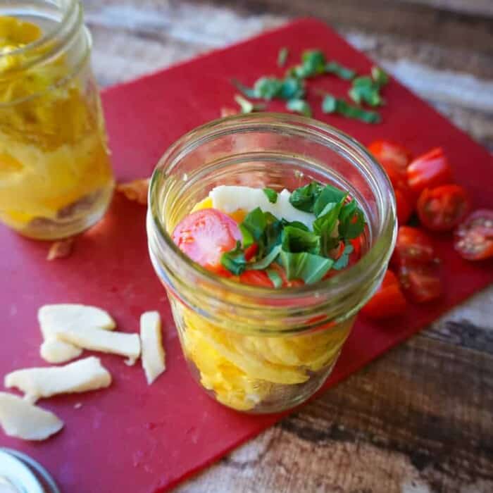 Eggs in a small mason jar topped with tomato, basil and cheese