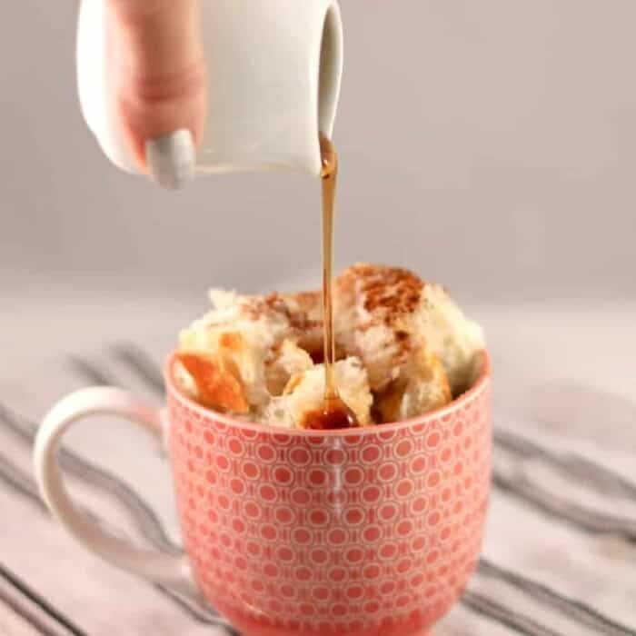 Maple syrup being poured over french toast in a mug