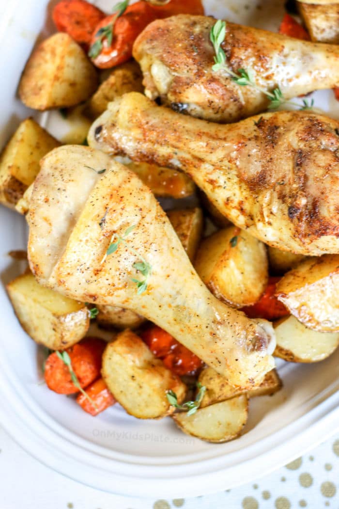 A close up of two golden  brown chicken legs on top of vegetables