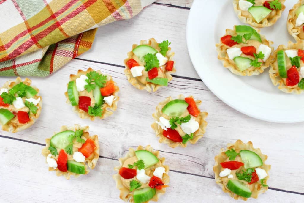  Party snack appetizers full of hummus, cucumber, red pepper and feta cheese on a table and plate