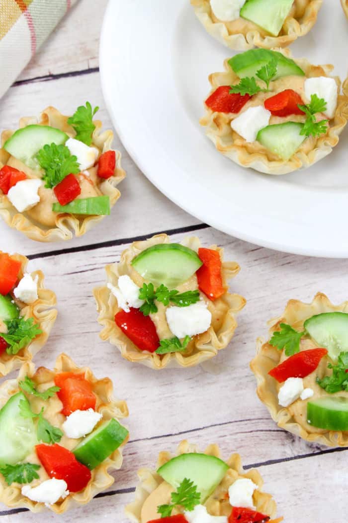 Hummus topped with feta cheese and vegetables in phyllo cups.