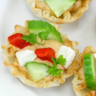 Close up of a party snack appetizer full of hummus, cucumber, red pepper and feta cheese.