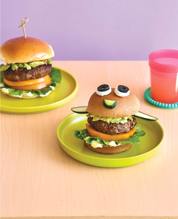 Beef and veggie burger decorated with condiments to look like a face on a plate.