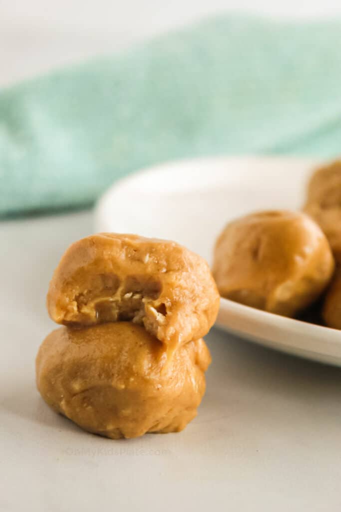 Peanut butter snack bites on a plate and next to the plate stacked, one with a bite missing