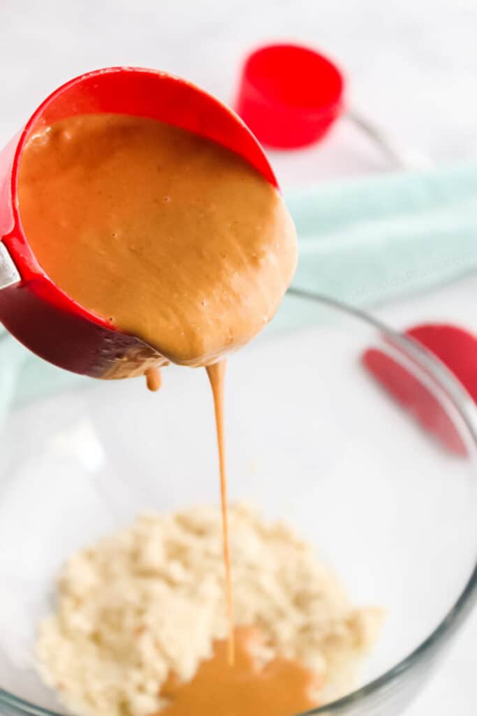 Adding peanut butter to a bowl of almond flour