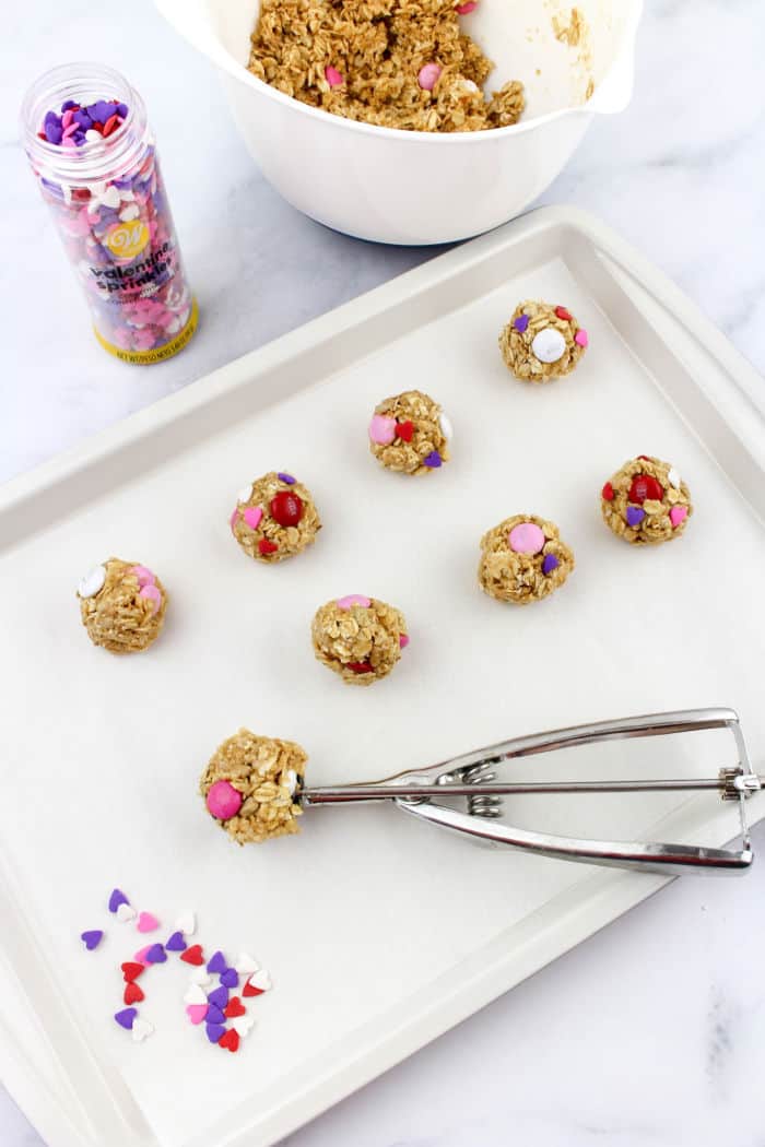 No bake snack bites being scooped and placed on a baking sheet.