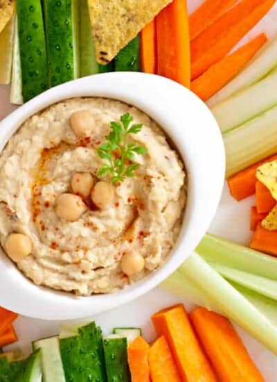 Hummus in a bowl with vegetables and tortilla chips