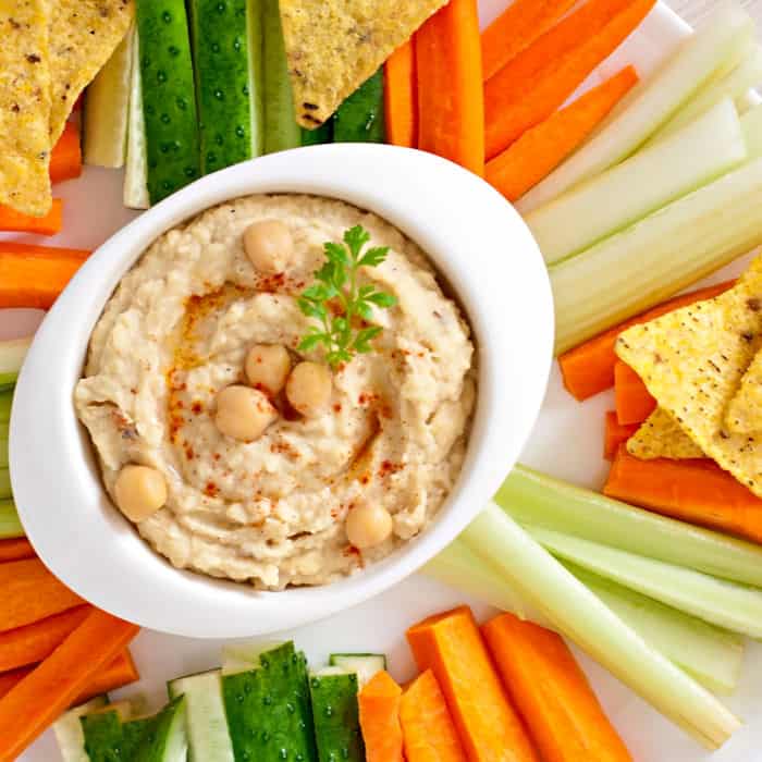 Hummus in a bowl with vegetables and tortilla chips