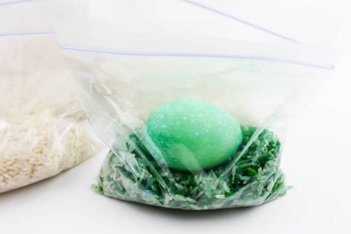 Egg in a bag colored green sitting on green colored rice.