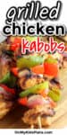 Grilled chicken skewers are grilled with peppers and onions and served on a platter with a text title overlay that says grilled chicken kabobs.