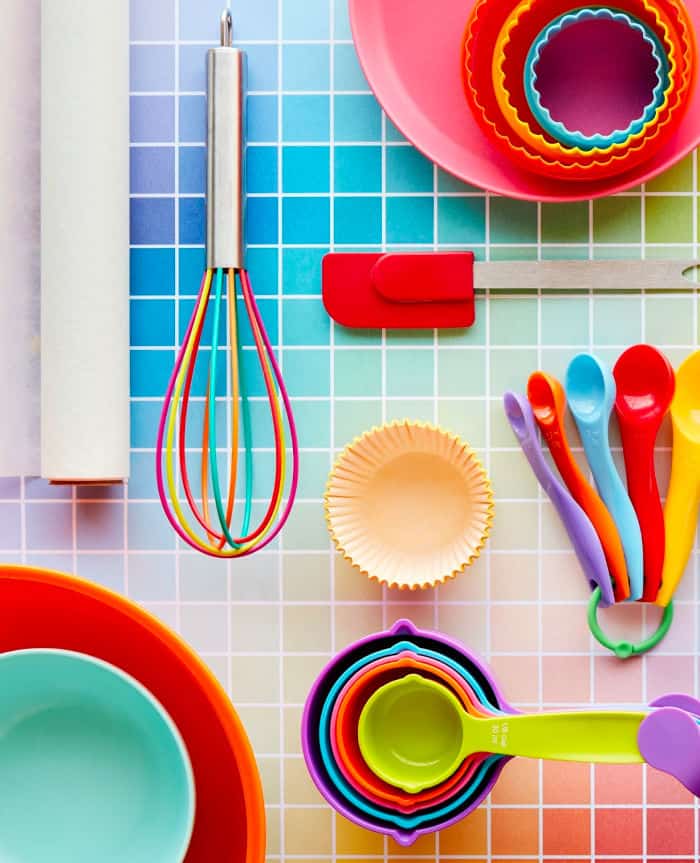 Colorful rainbow baking supplies sit on a colorful grid
