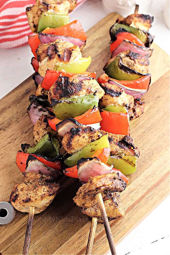 Marinated chicken kabobs on a wooden cutting board.