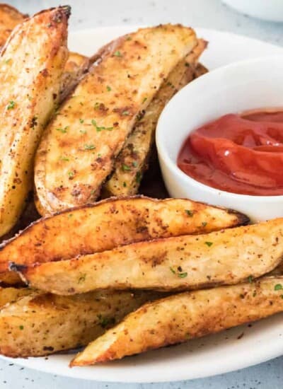 Potato wedges close up on platter with ketchup in a bowl