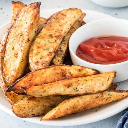 Potato wedges close up on platter with ketchup in a bowl