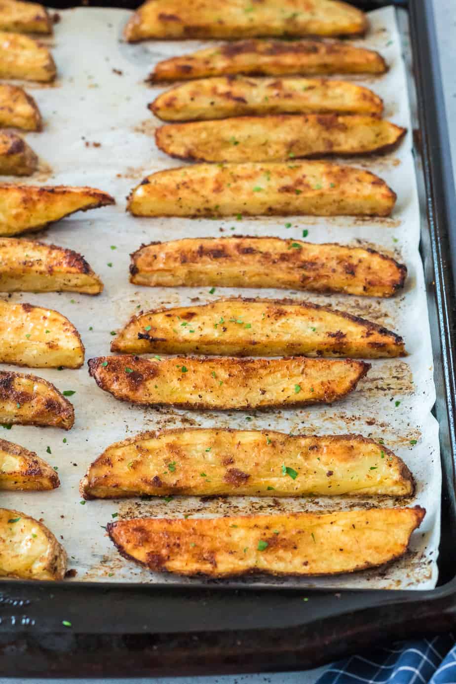 crispy brown potato wedges after baking on the pan at an angle