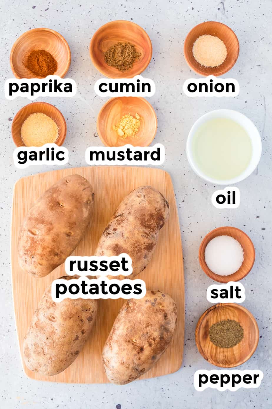 Ingredients for potato wedges on a counter in bowls with labels