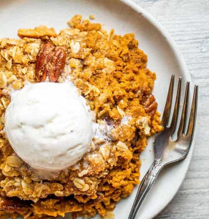 Pumpkin crisp on a plate overhead with a fork and whipped cream