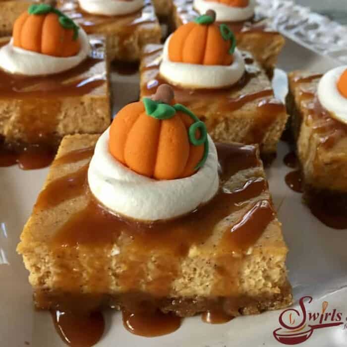 Dessert bars covered in caramel, whipped cream and a candy pumpkin.