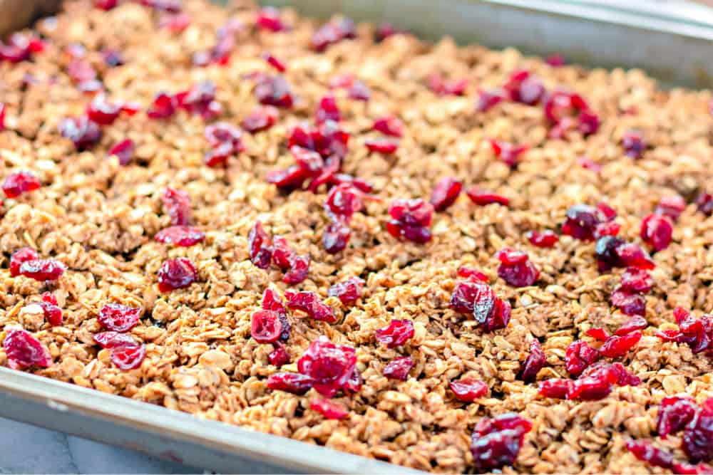 Baking pan full of granola sprinkled with cranberries