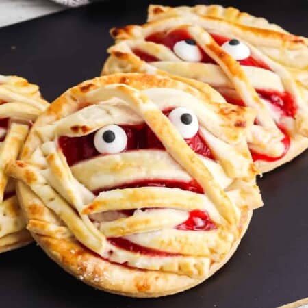 Close up of two cherry hand pies decorated like mummies