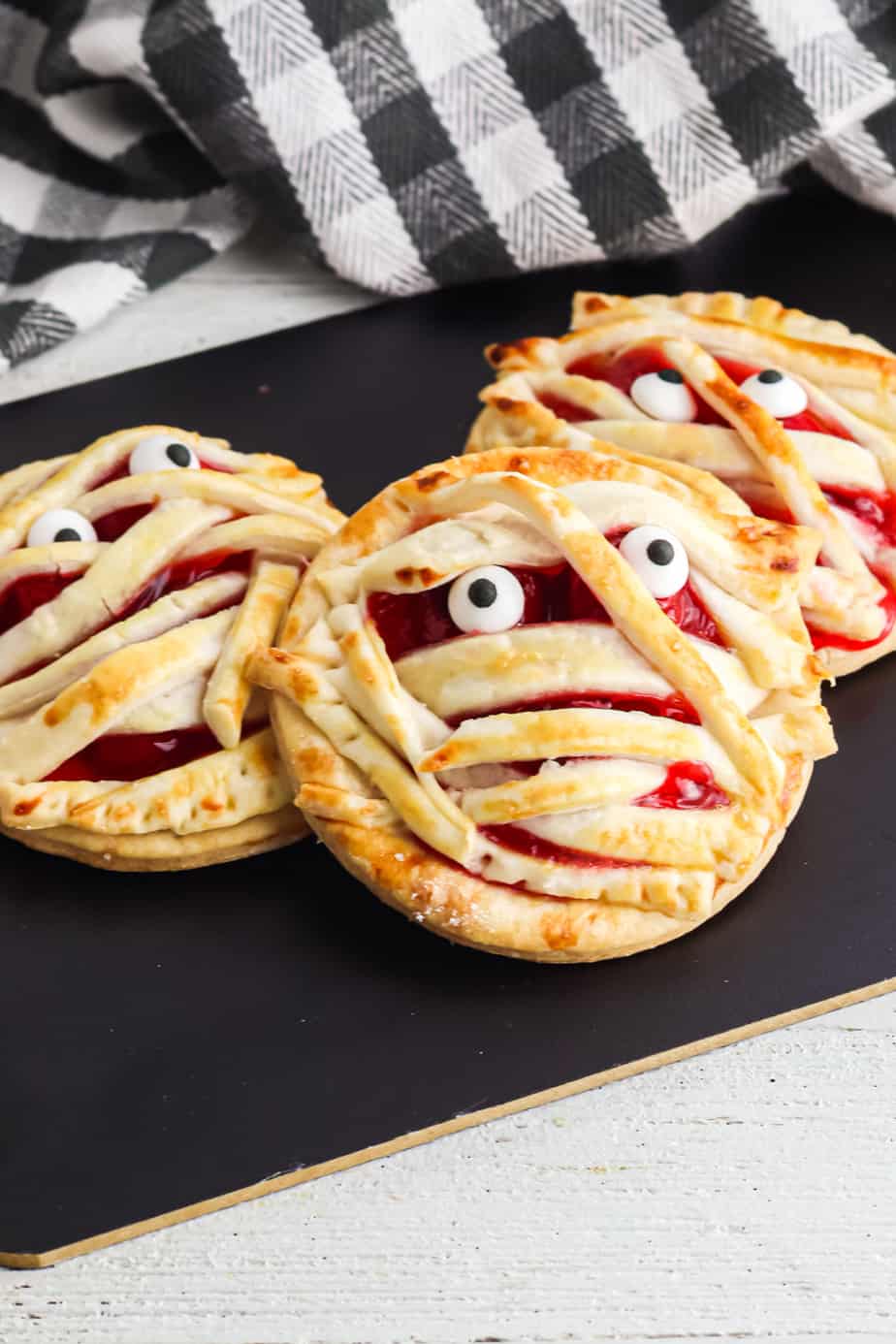 round cherry hand pies that have been baked and decorated to look like mummy faces