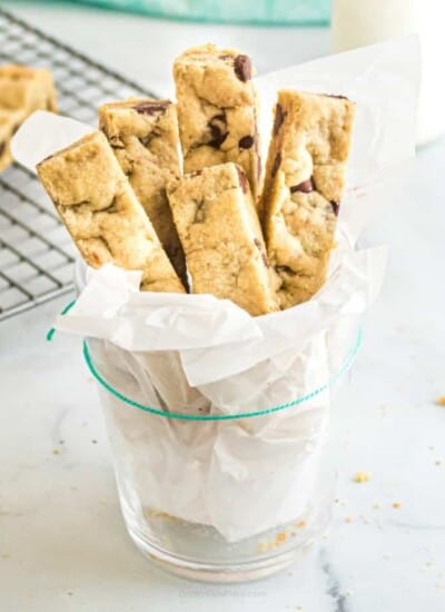 Chocolate cookie sticks served in a glass lined with parchment paper.