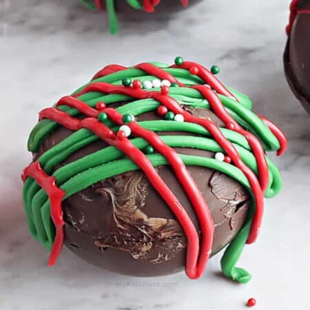 Close up of a chocolate hot cocoa bomb with red and green decorations