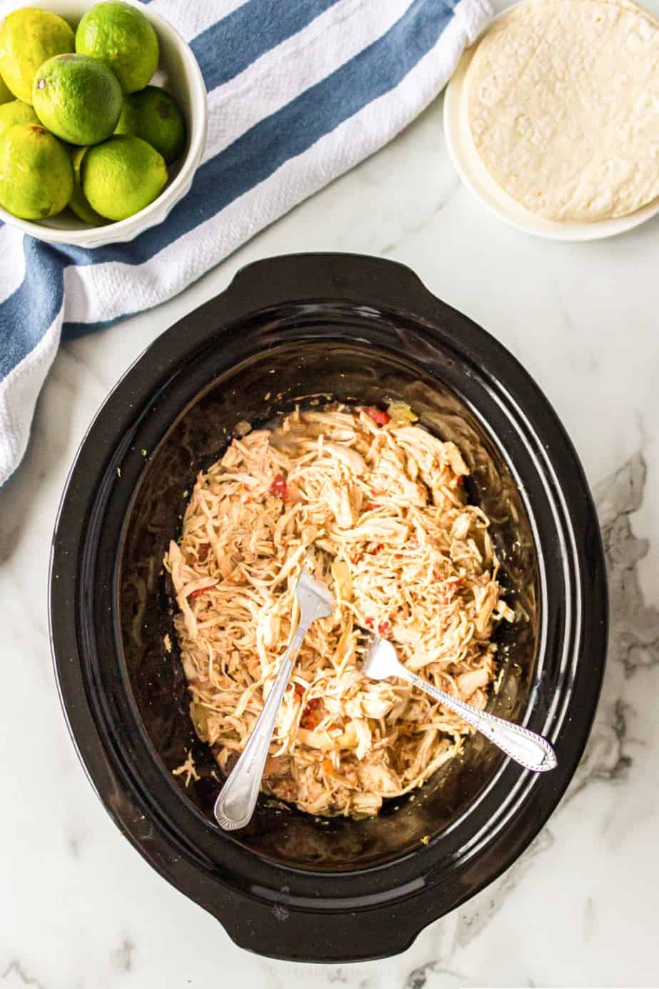 Chicken shredded in a crockpot from overhead with two forks.