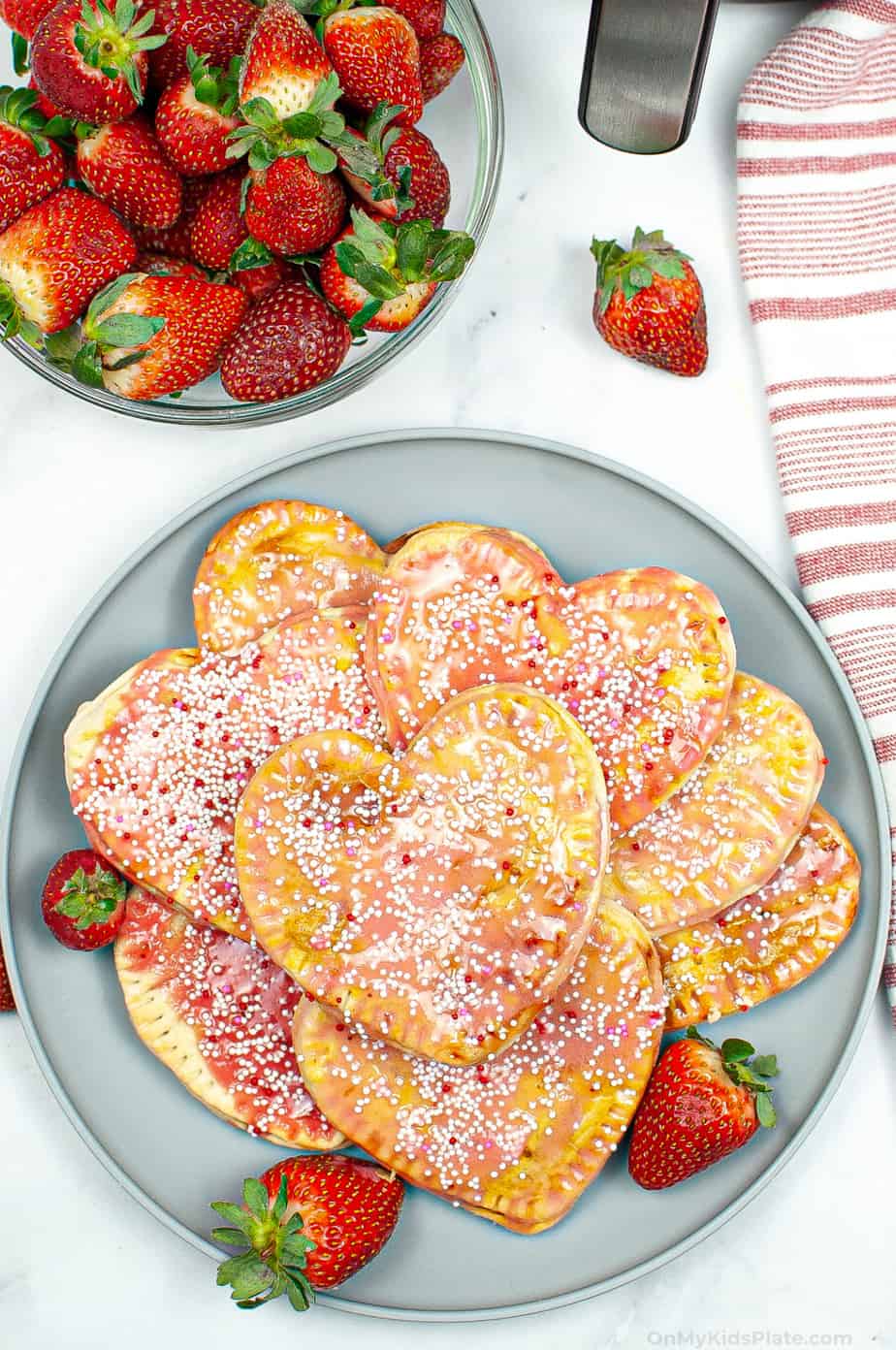 A platter of strawberry pop tarts from overhead with a bowl of strawberries