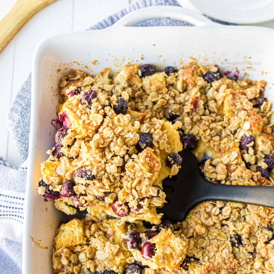 Pan of blueberry french toast casserole from overhead being scooped out of the pan.