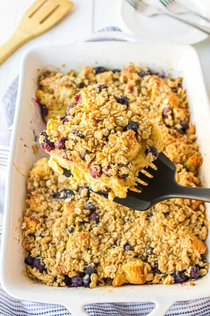 Golden blueberry french toast casserole baked and topped with streusel topping being scooped with a spatula