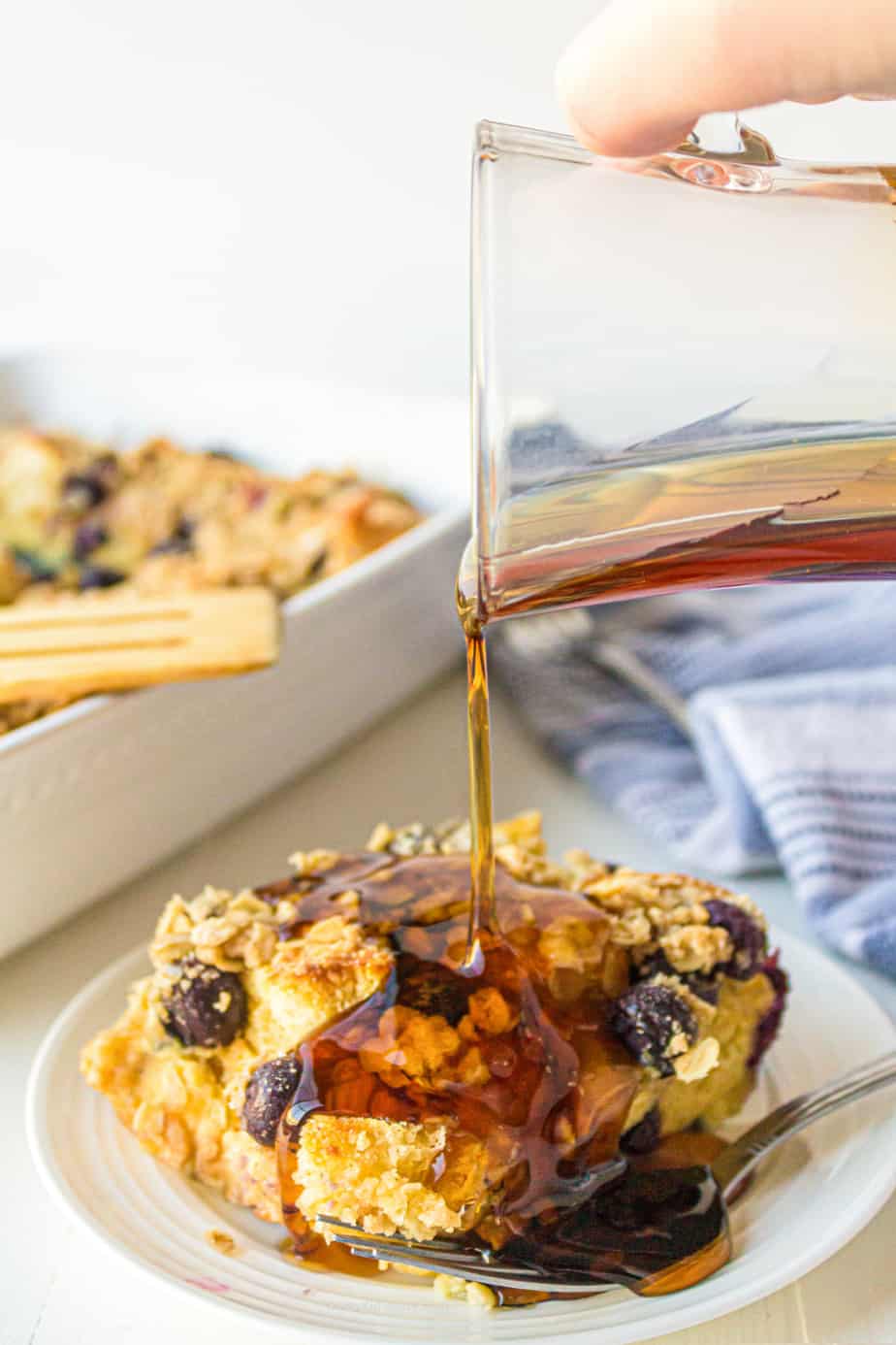 Piece of blueberry french toast casserole with maple syrup being drizzled on top