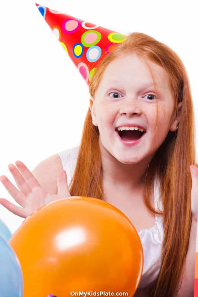 Girl laughing with birthday hat and balloons