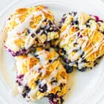 Three blueberry biscuits with glaze on a plate