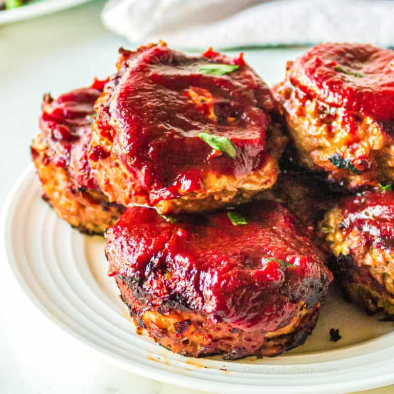 Close up side vie of mini turkey meatloaf muffins on a plate topped with bbq sauce