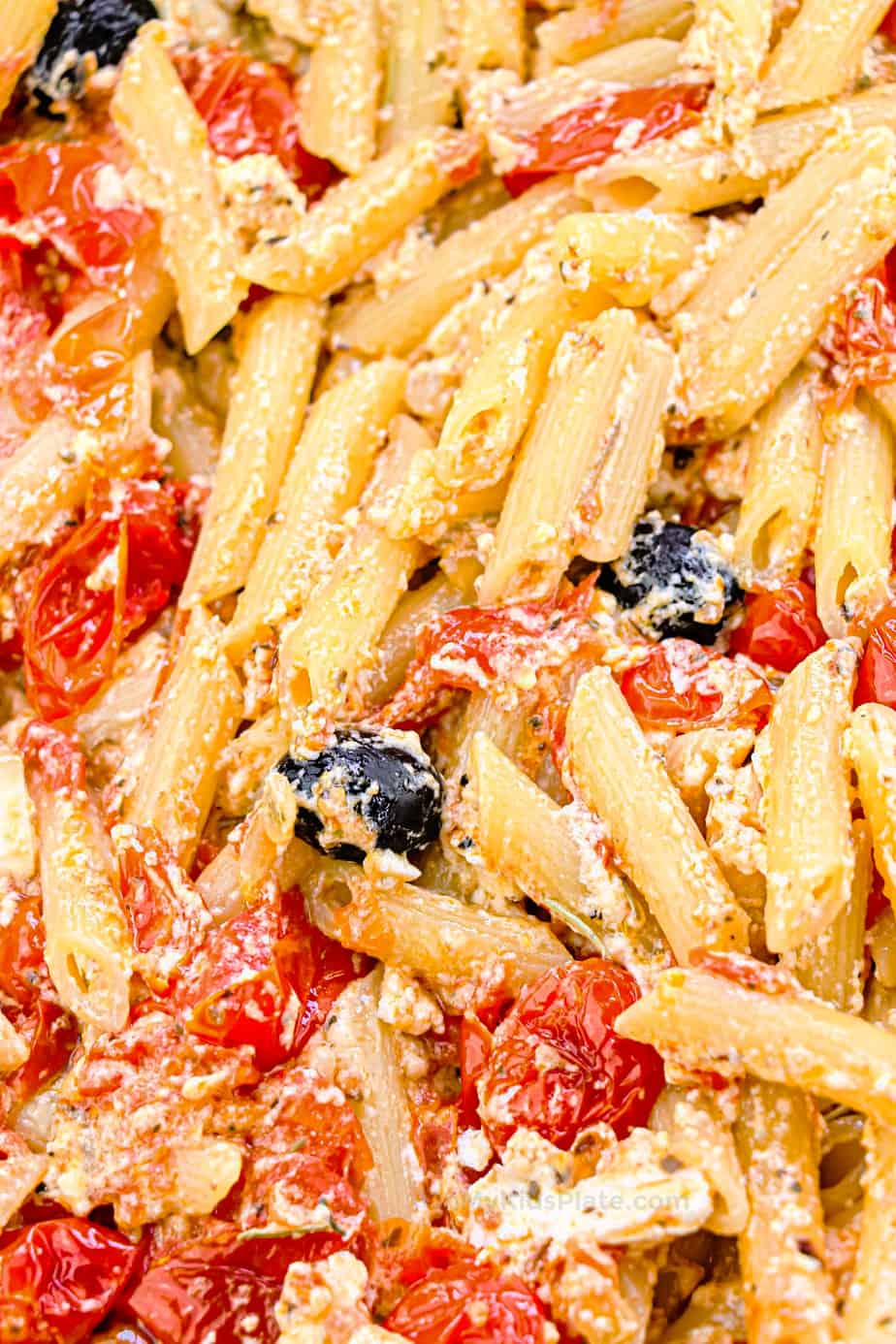 Close up of penne pasta with roasted tomatoes, olives and feta cheese.