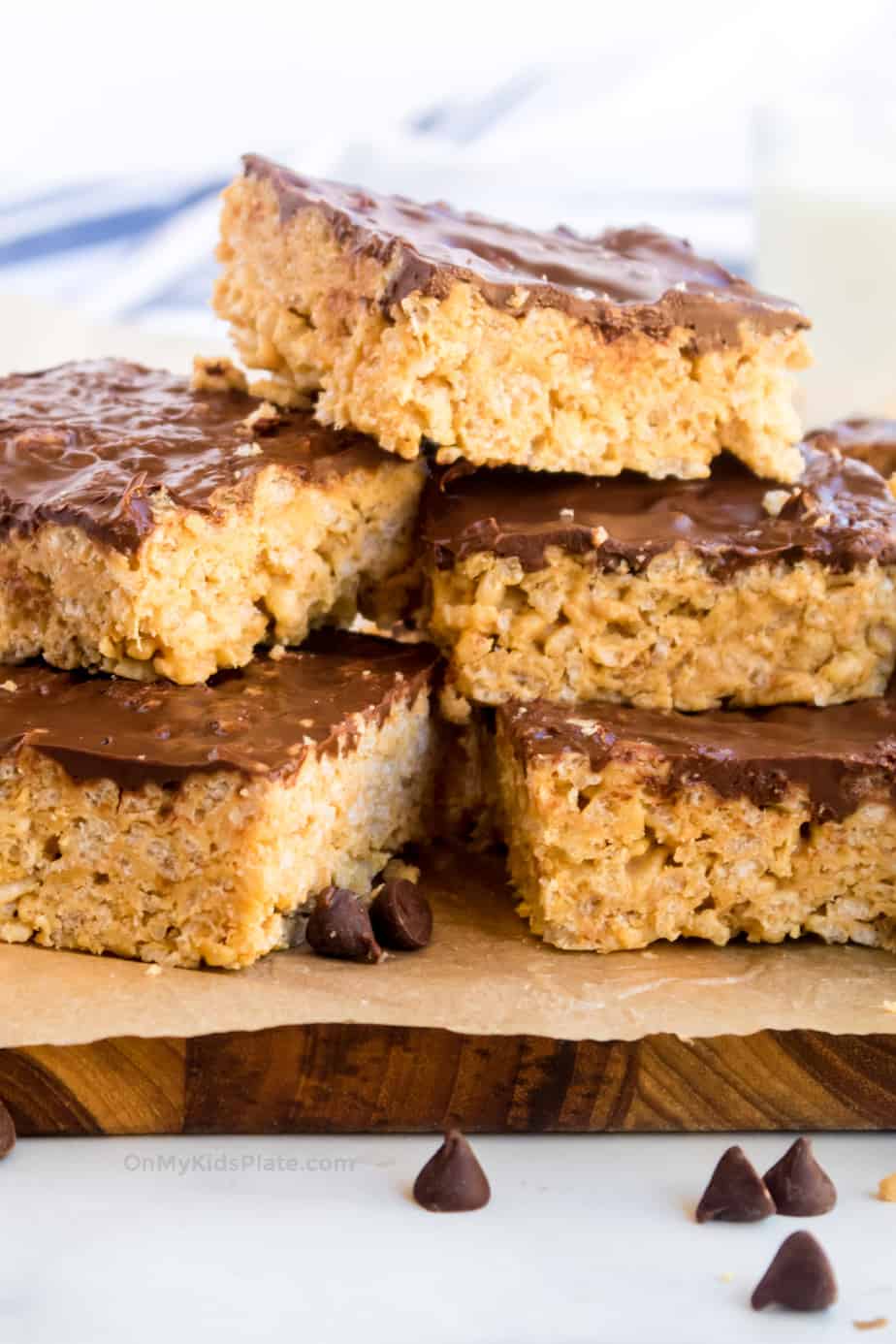 Peanut butter chocolate rice krispie treats stacked three high on a cutting board.