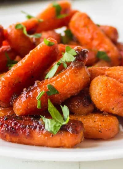 Close up side vide of glazed baby carrots piled on a plate.