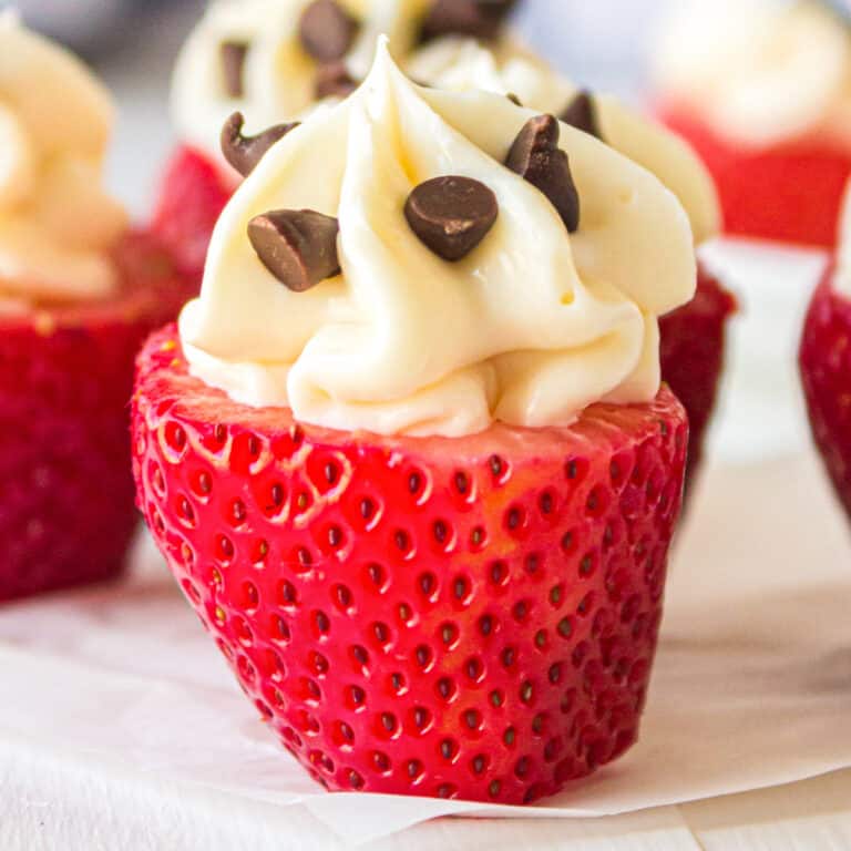 Close up side view of a strawberry standing on end filed with swirled cheesecake filling and mini chocolate chips.