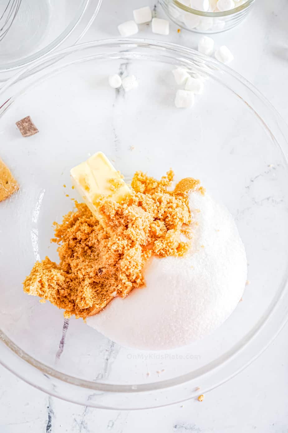 A clear bowl with softened butter, white sugar and brown sugar.