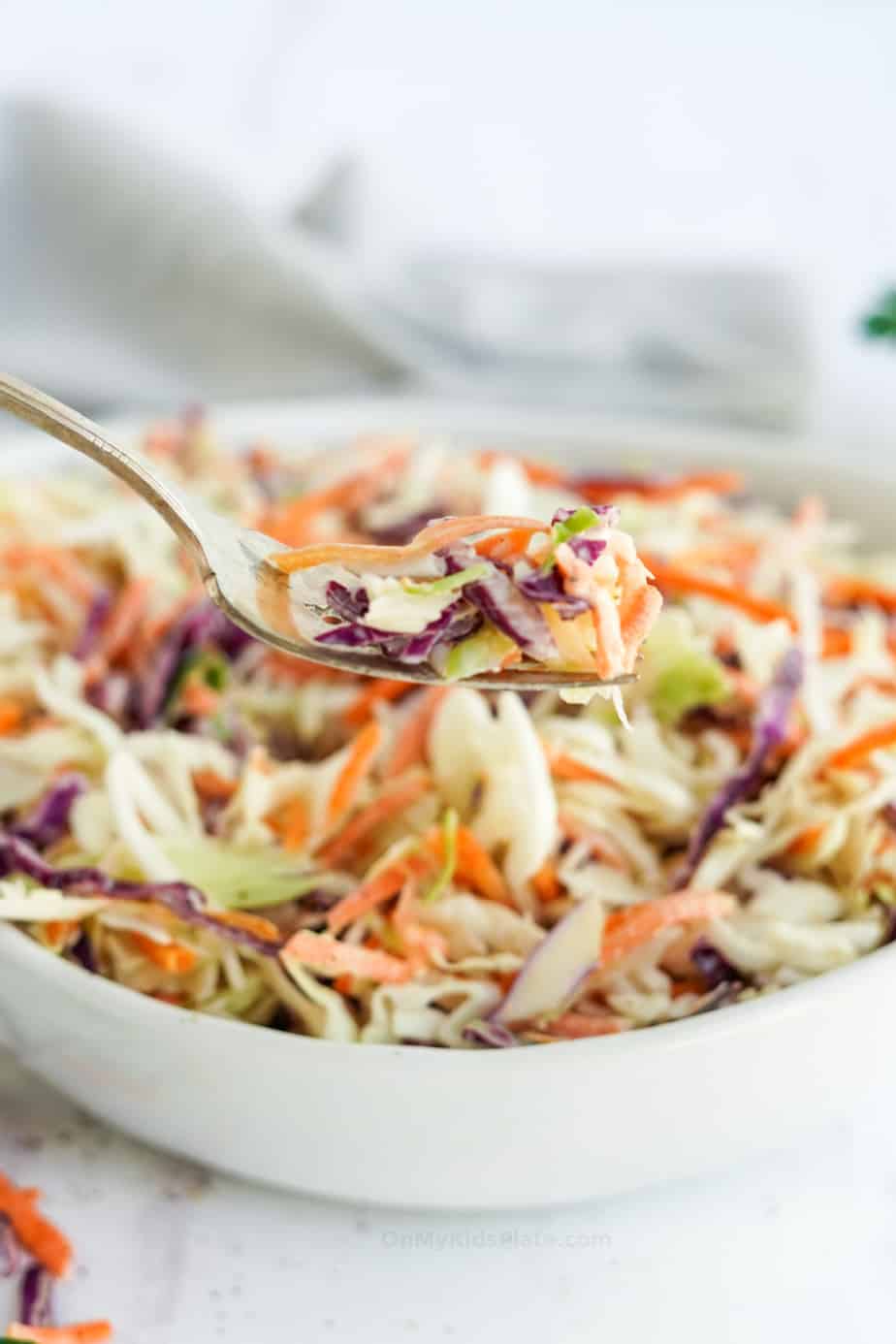 Coleslaw in a bowl being lifted up on a fork