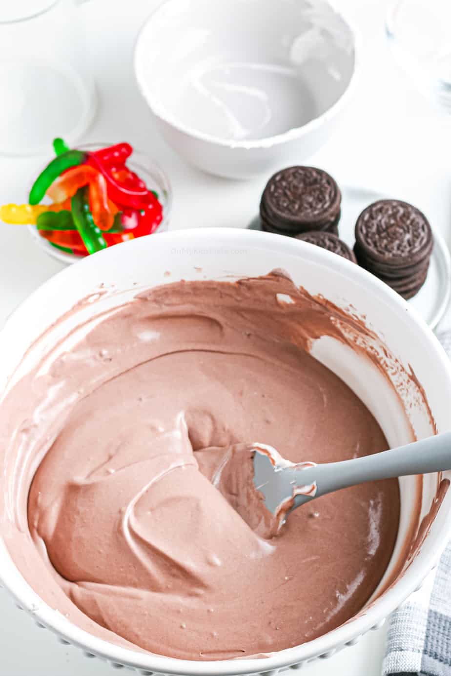 Chocolate pudding and whipped topping mixed together with a spatula in a bowl.