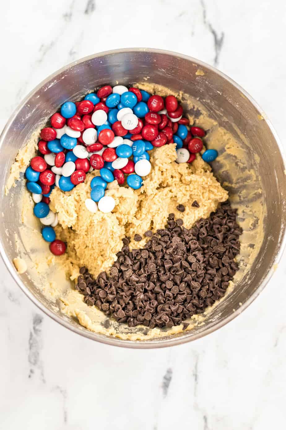 Cookie dough with red white and blue M&Ms and chocolate chips in a bowl.