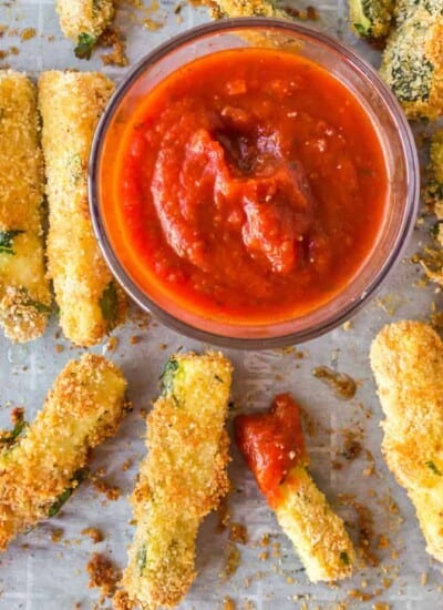 Zucchini fries on a pan overhead with marinara in a bowl to dip