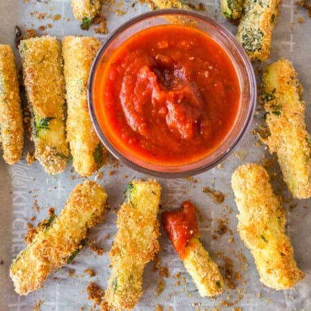Zucchini fries on a pan overhead with marinara in a bowl to dip