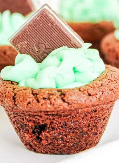 Close up of a chocolat4e cookie cup filled with frosting and a chocolate mint candy on a serving tray