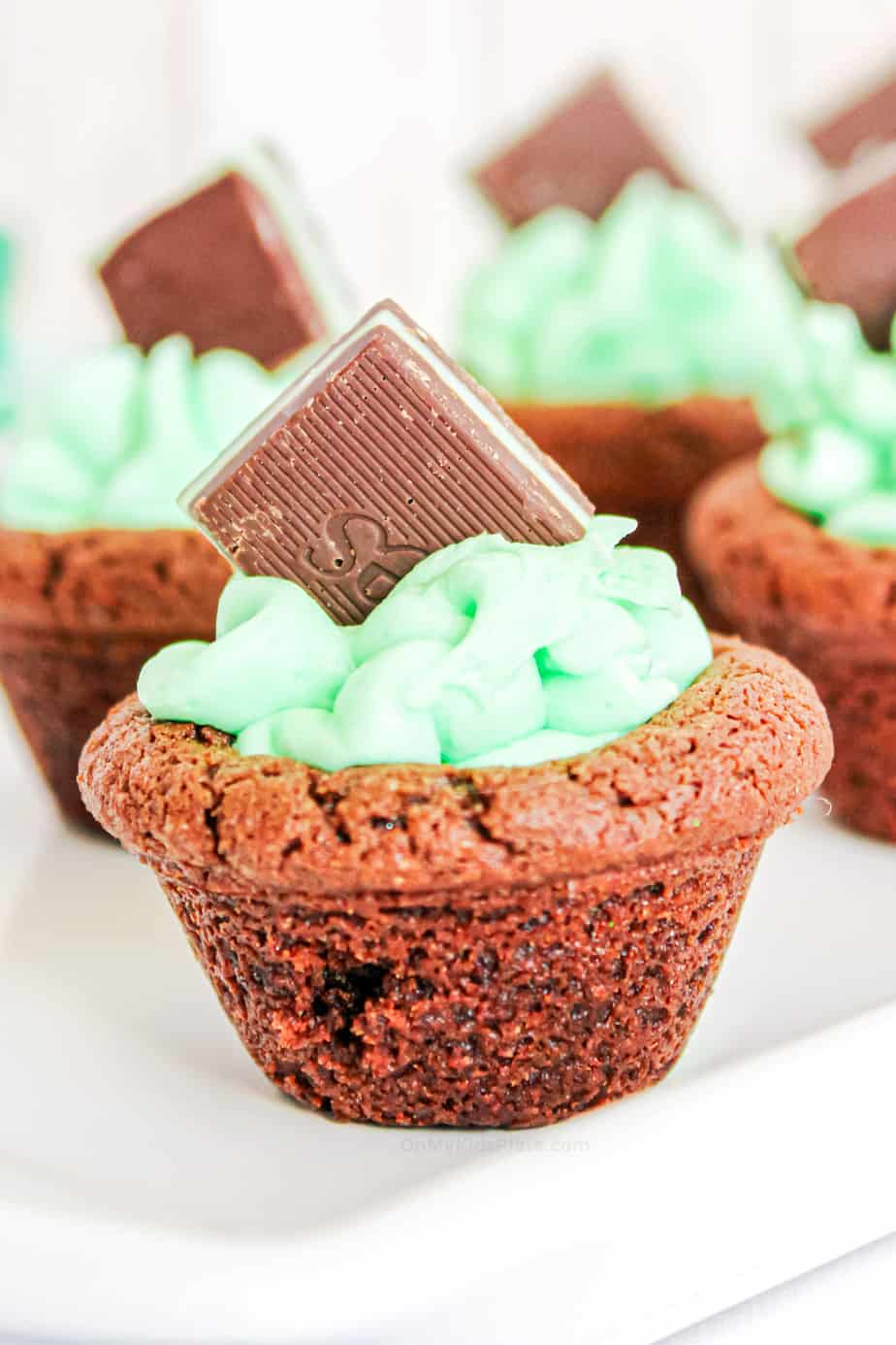 Chocolate cookie cup up close filled with mint frosting topped with a chocolate Andes Mint.