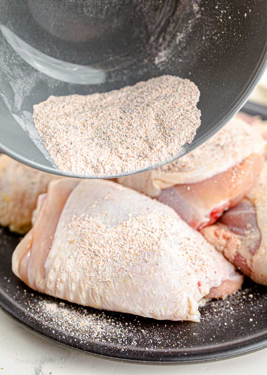 Adding spices and baking powder to chicken thighs