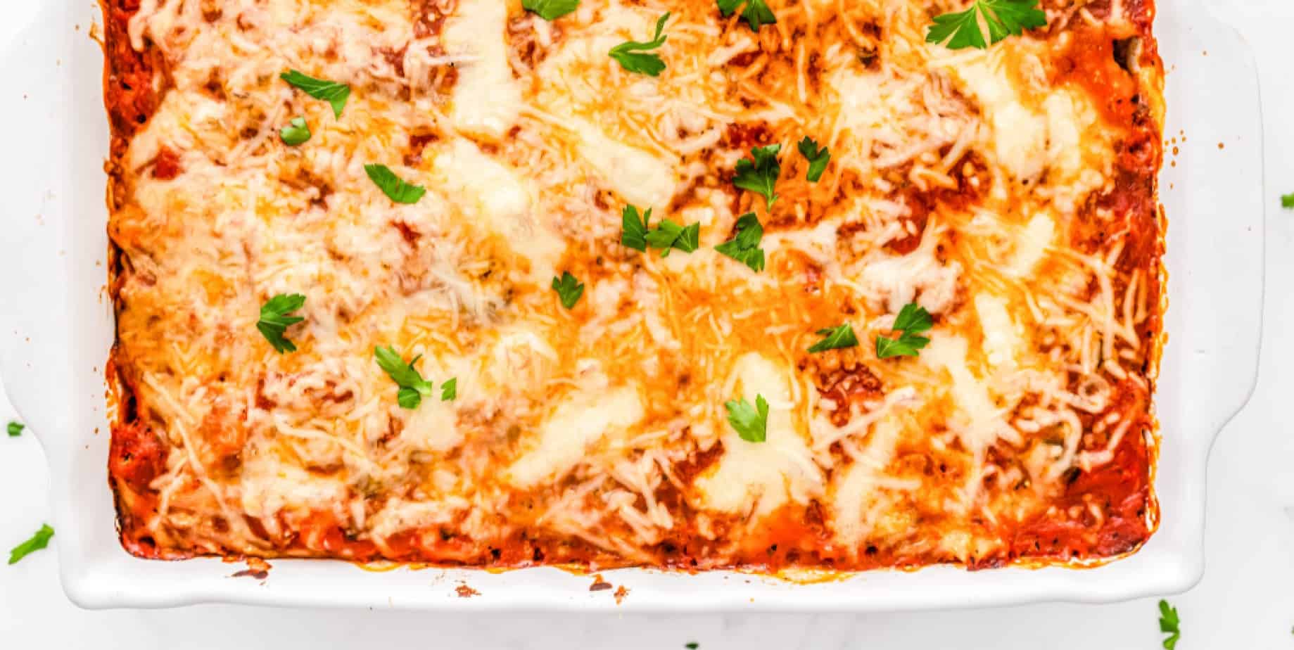 Baked Ziti covered in cheese from overhead in a pan.