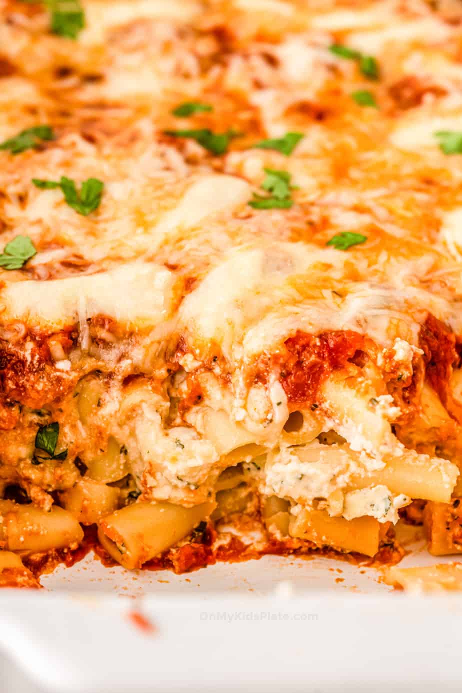 Close up of baked ziti with ricotta, tomato sauce and gooey mozzarella cheese on top.